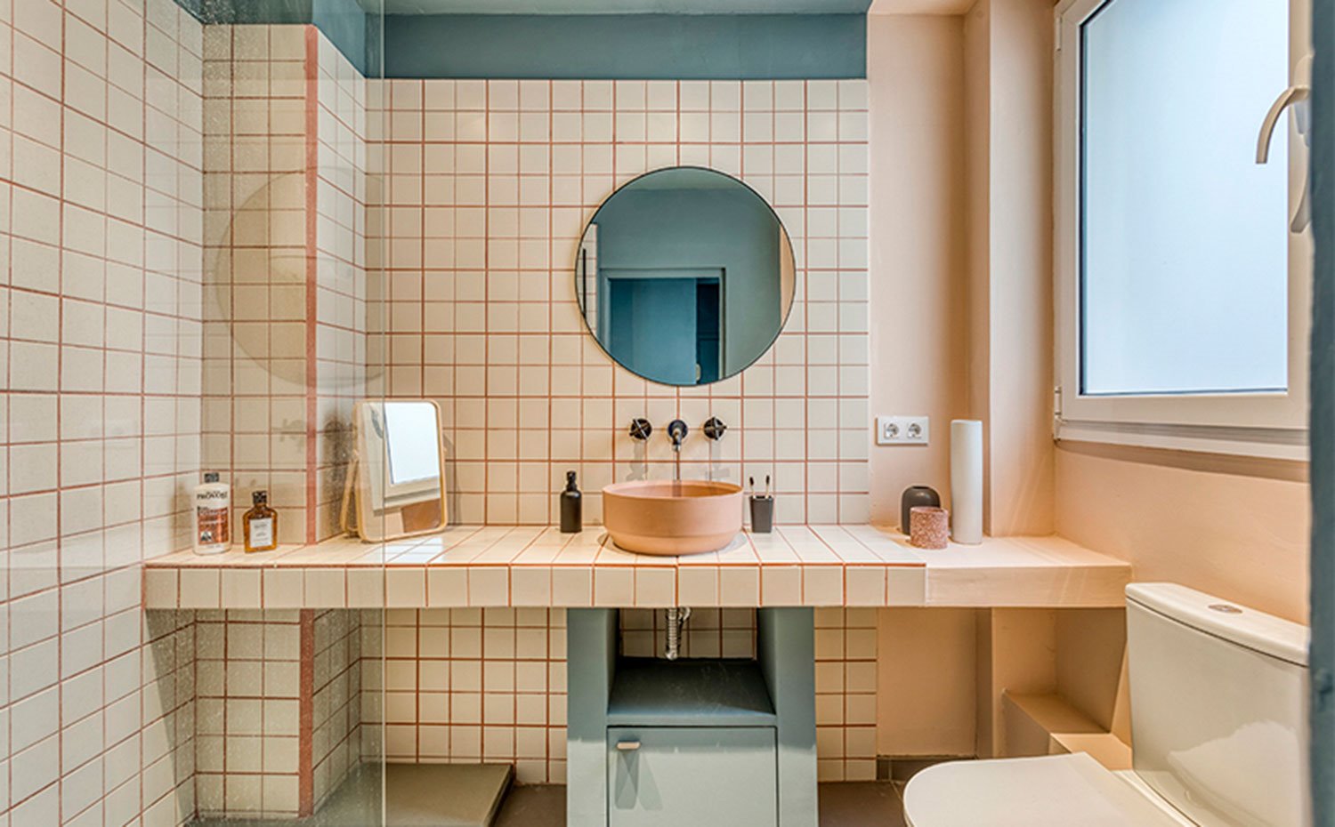 Cuarto de baño con encimera de tocador de obra, con lavamanos en rosa y módulo inferior en azul turquesa