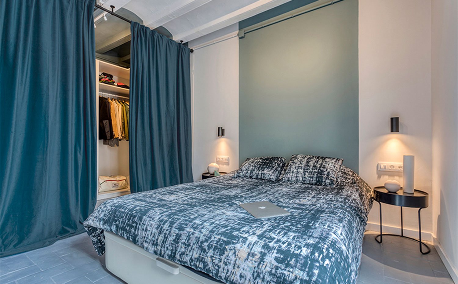 Dormitorio principal con mesillas y apliques en negro, pared pintada a franjas delimitando la zona de cama, techo abovedado