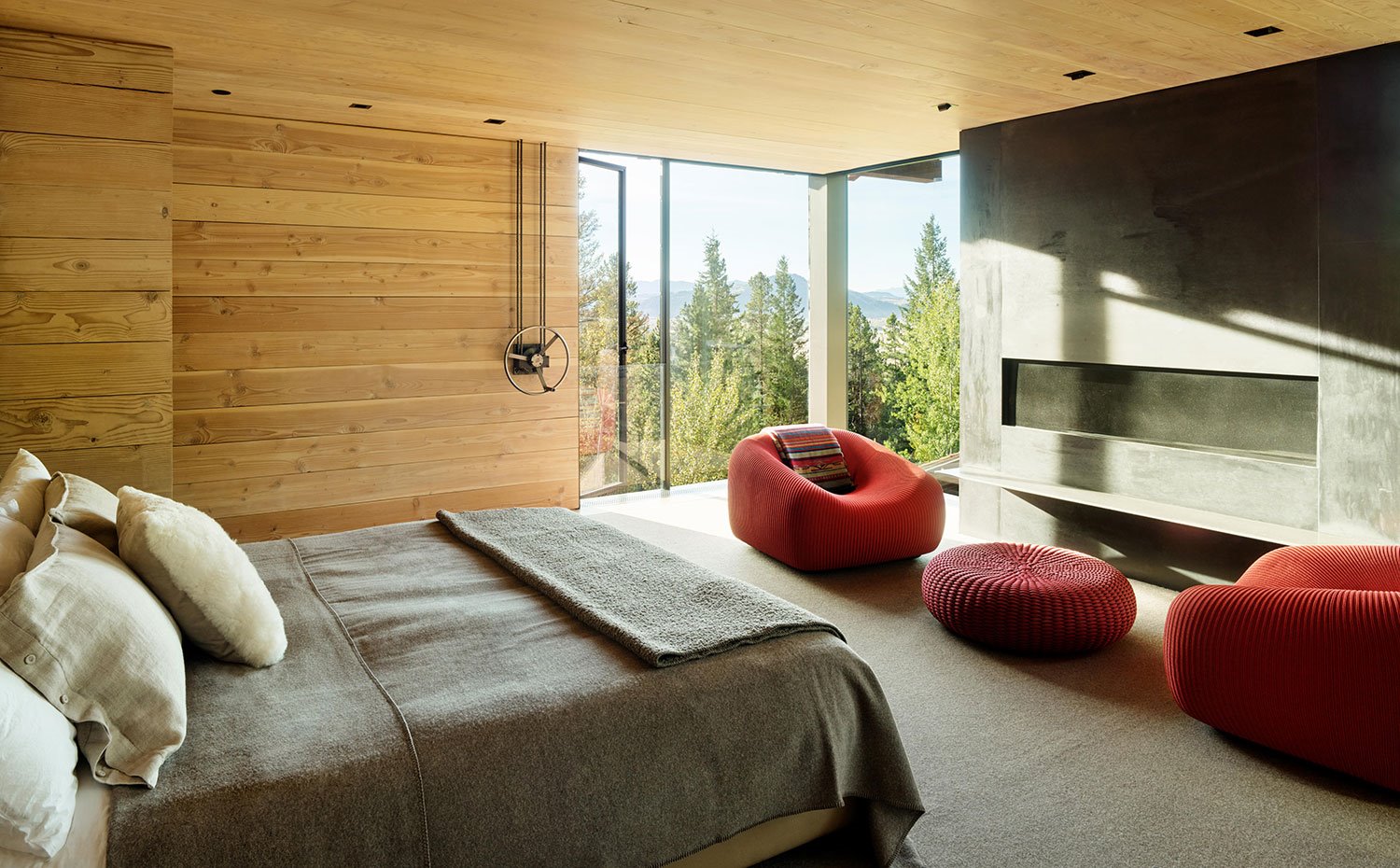 Dormitorio con chimenea, butacas en naranja, paredes y techos en madera, lencería de lino