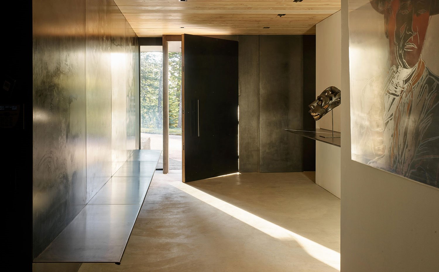 Puerta de acceso con banco y pared en hierro oxidado y techo de madera