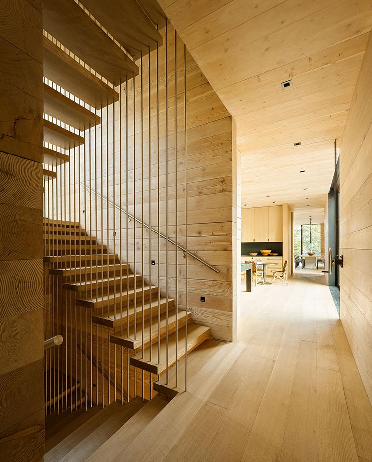 Zona de paso con escaleras de madera y vista hacia comedor y cocina 