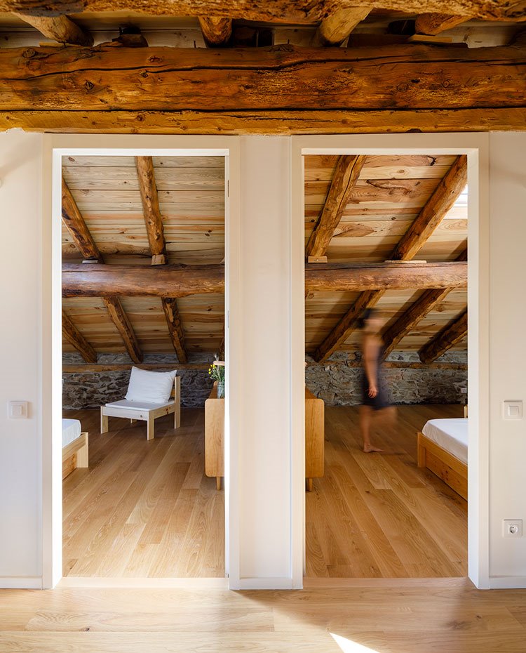 Detalle de dos dormitorios contiguos con techo abuardillado y suelo de madera