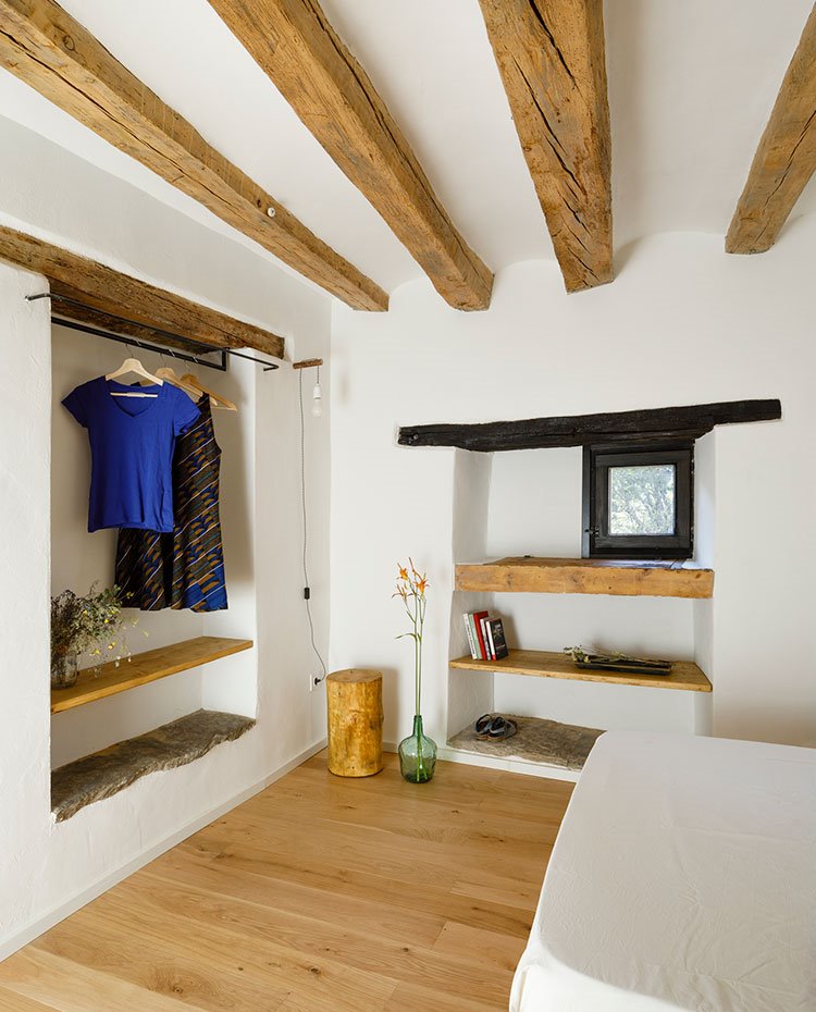 Dormitorio con hornacinas en pared con estantes de madera para el almacenaje, suelo de madera
