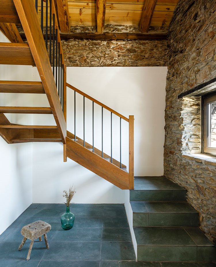 Escaleras de madera y tres peldaños en hormigón, pared de piedra combinada con enyesado.