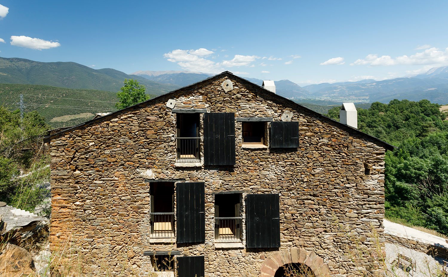 Fachada exterior vivienda de piedra con balcones y porticones de madera