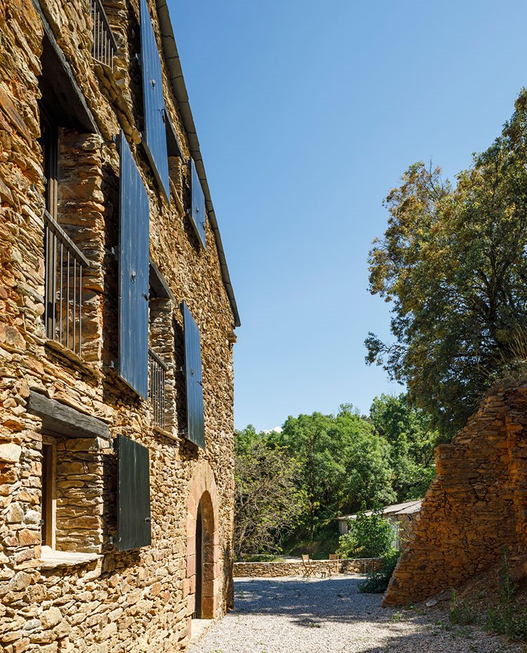 Lateral de fachada con camino de piedra y fachada de piedra seca