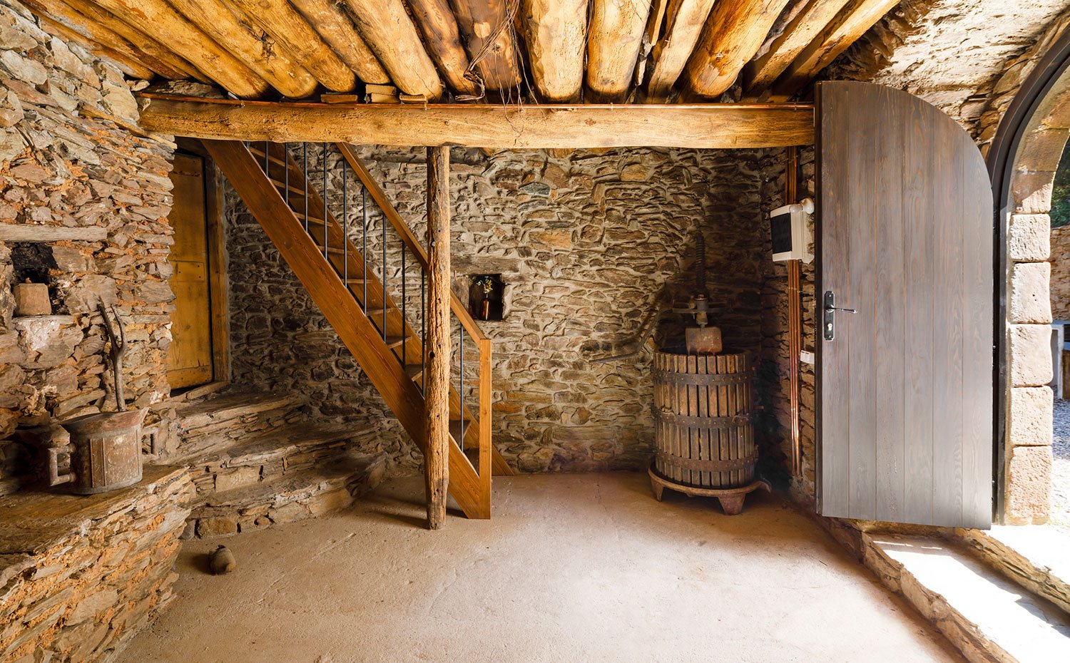 Puerta de acceso de madera, estrura y paredes de piedra, escaleras de madera y vigas antiguas de madera