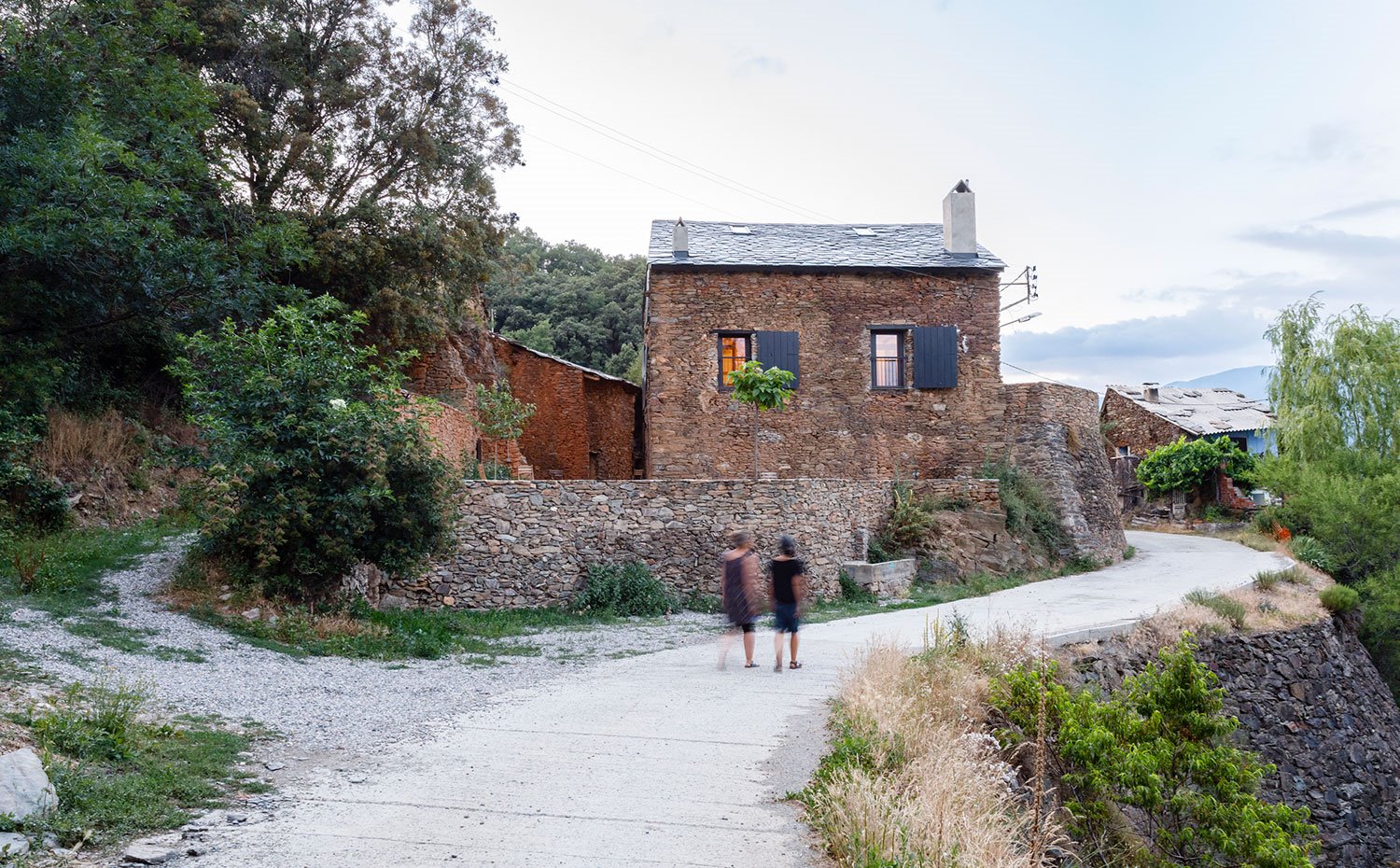 Vista exterior de la vivienda en ambiente rural con camino de acceso de piedra