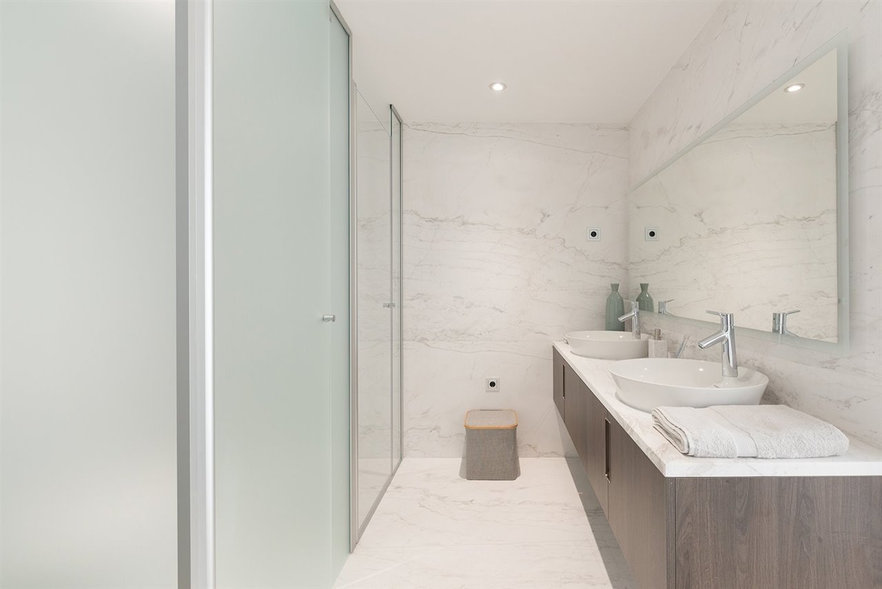 En los baños se combina el mármol travertino con el gres porcelánico y la madera laminada para el mueble bajo encimera.