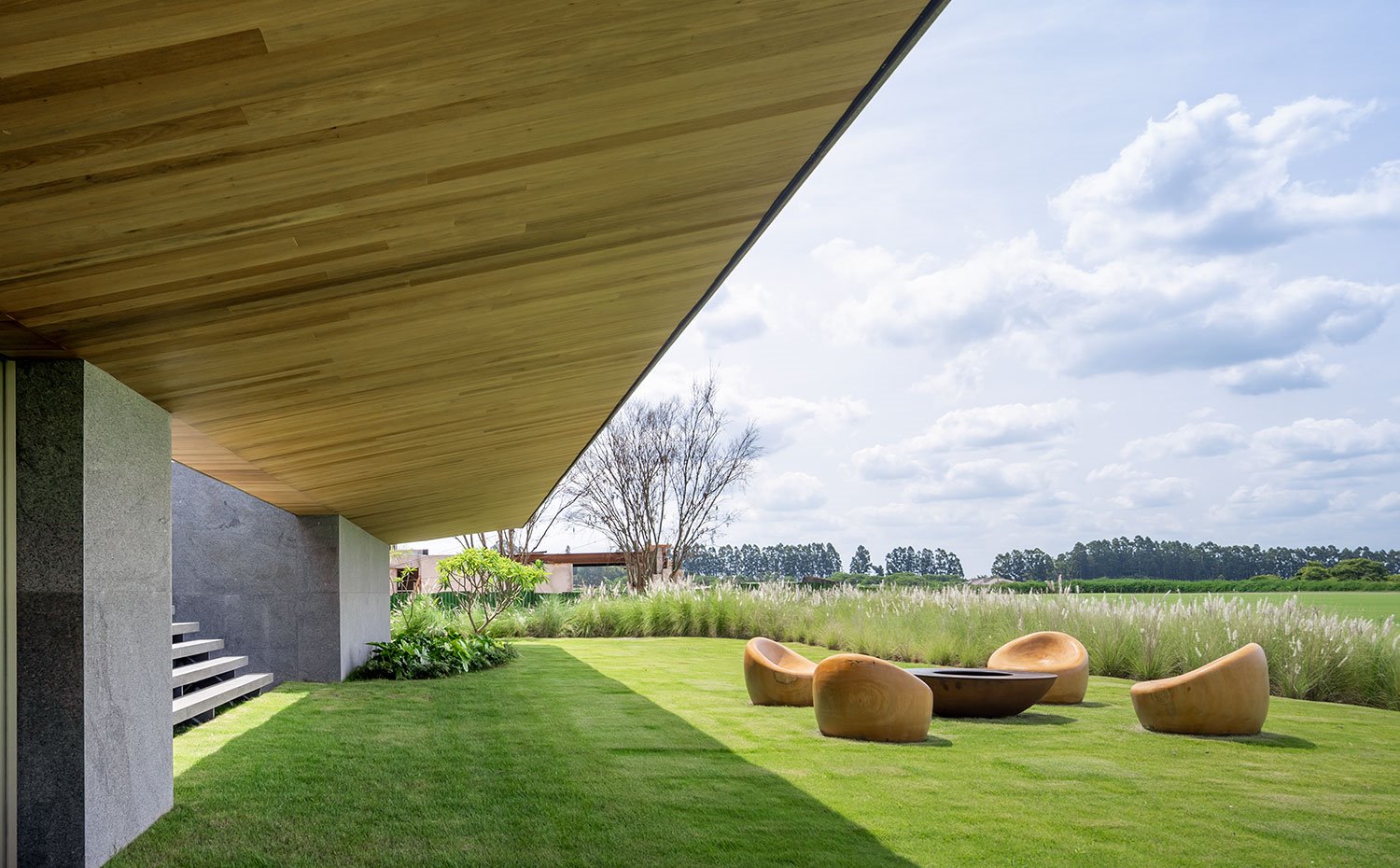 Terraza junto asientos y chimenea exterior con voladizo revestido de madera