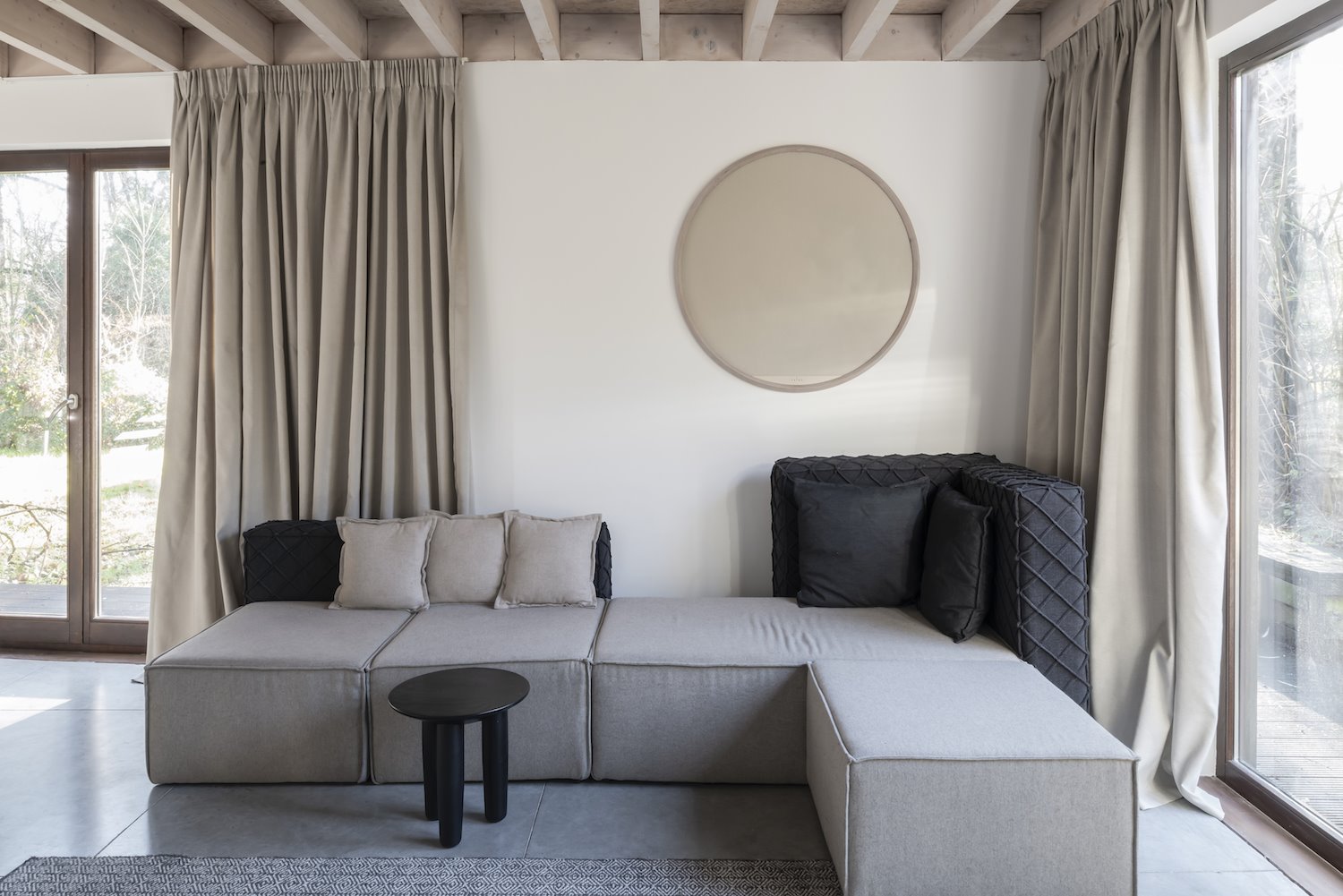 Salon con sofá modular de color gris y cortinas ocres