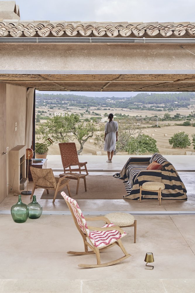 Butaca junto al salon abierto con tejado de teja Casa en Mallorca del estudio de arquitectura OHLAB