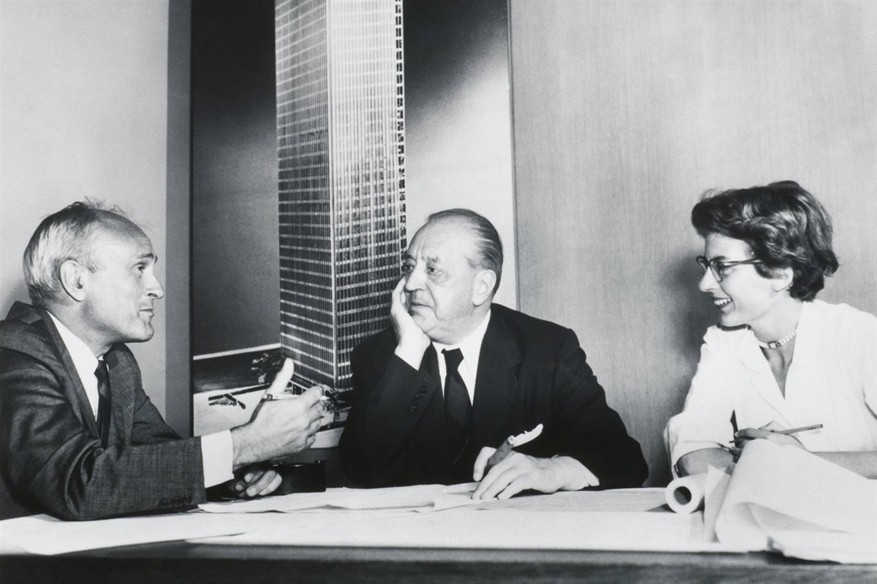 Philip Johnson, Mies van der Rohe y Phyllis Lambert (también arquitecta y heredera del imperio Seagram) frente a una imagen de la Torre Seagram de Nueva York.