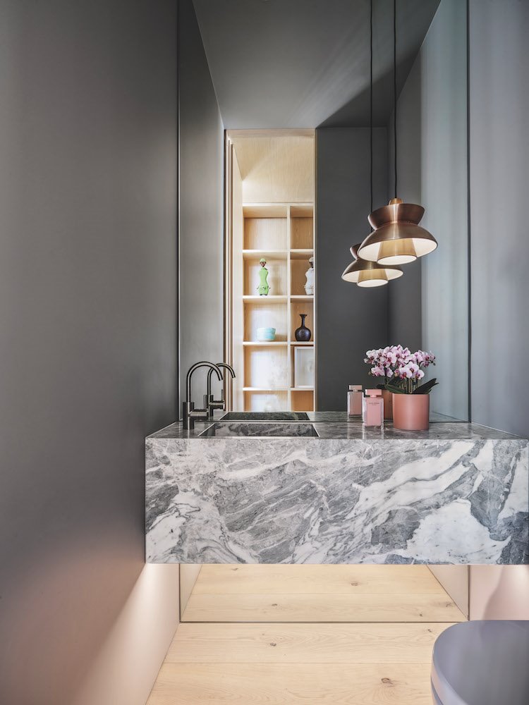 baño con pared de espejo y lavamanos de piedra natural