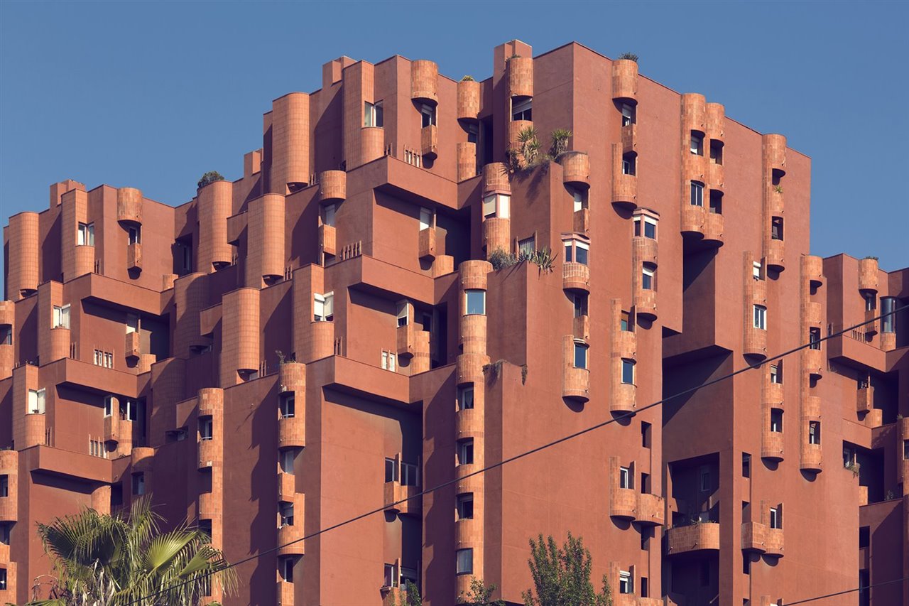 La fachada exterior presenta el aspecto de una enorme fortaleza pintada de rojo, que se abre al exterior a través de grandes aperturas a varios niveles como ventanas urbanas.