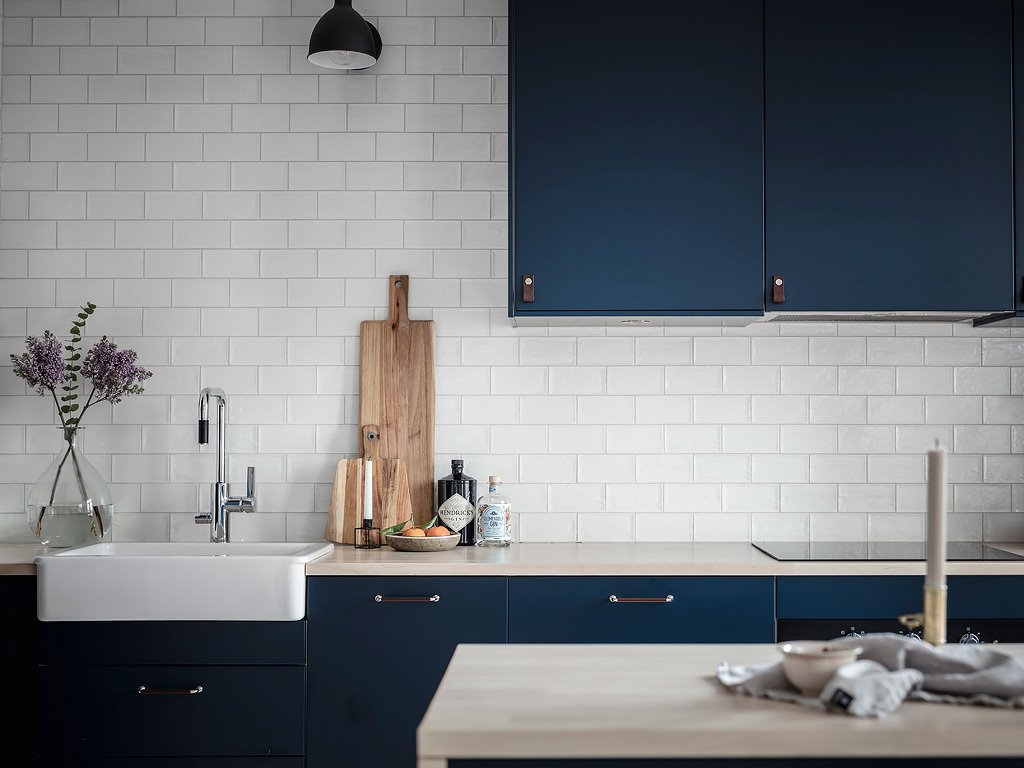 Cocina con pared de baldosas blancas y muebles azules