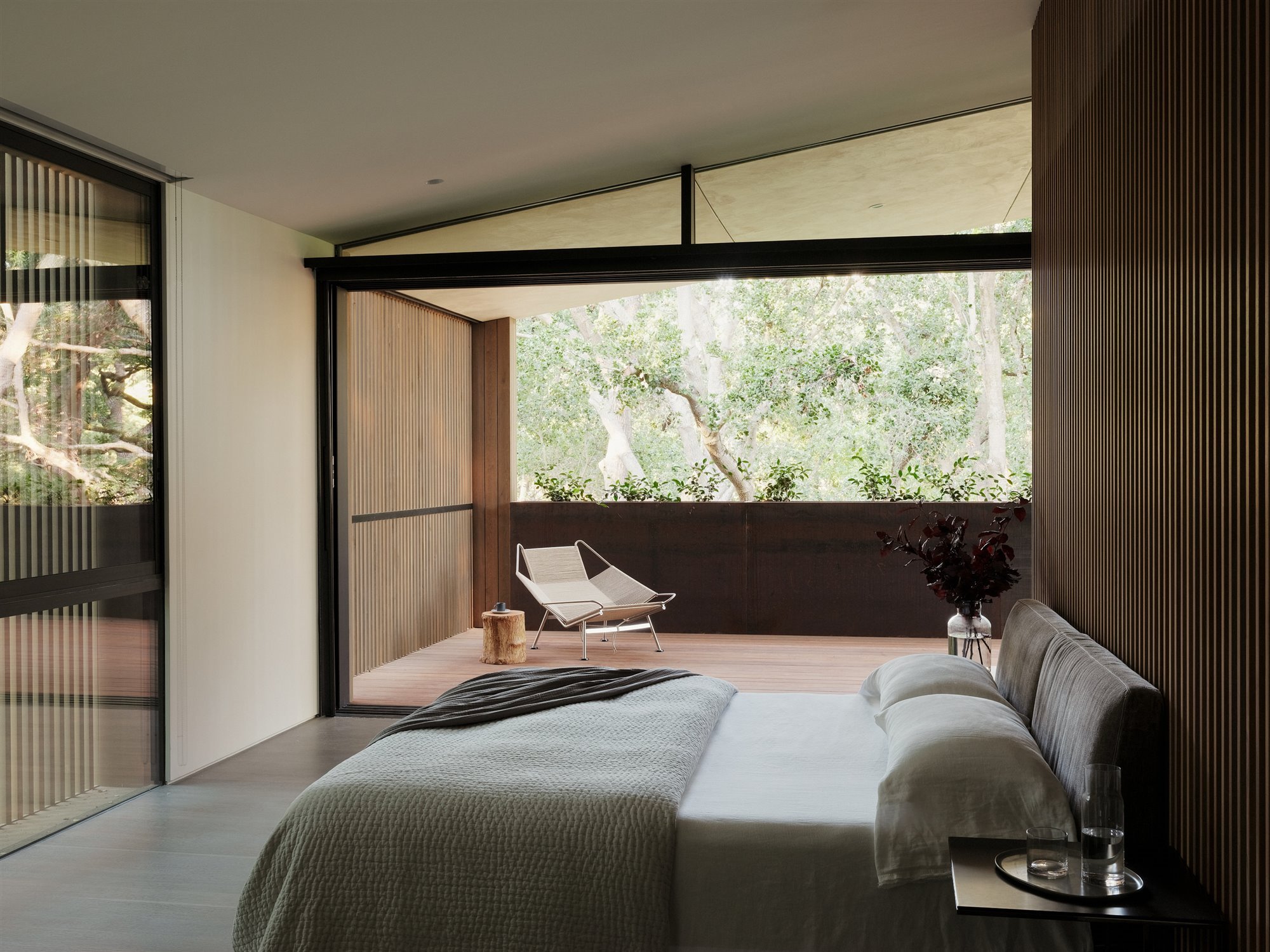Dormitorio con paredes paneladas de madera y terraza