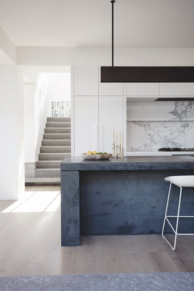 Cocina con frontal de piedra y silla alta de color blanco
