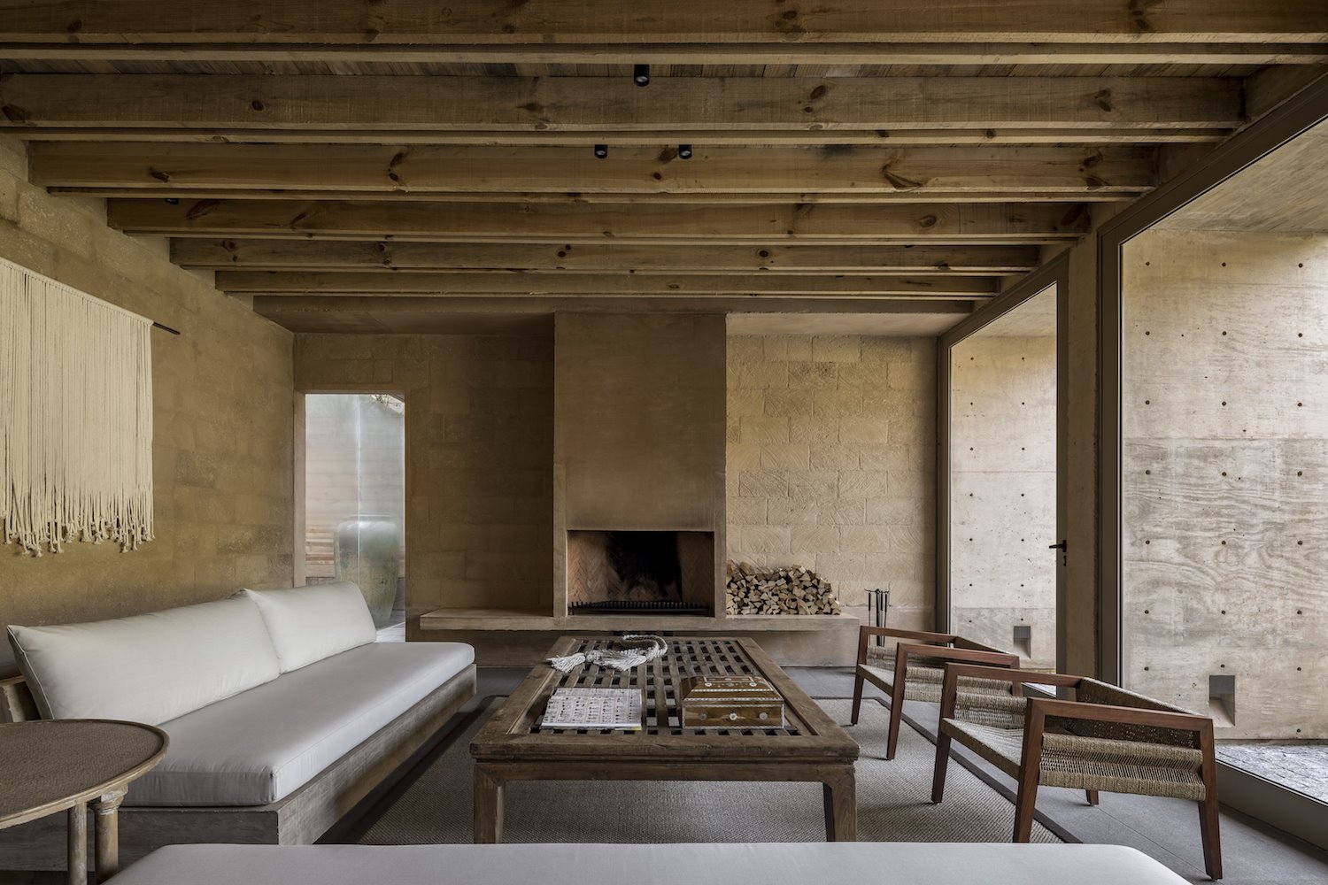 Salon con paredes de piedra y vigas de madera casa arquitecto Hector Barroso en Mexico