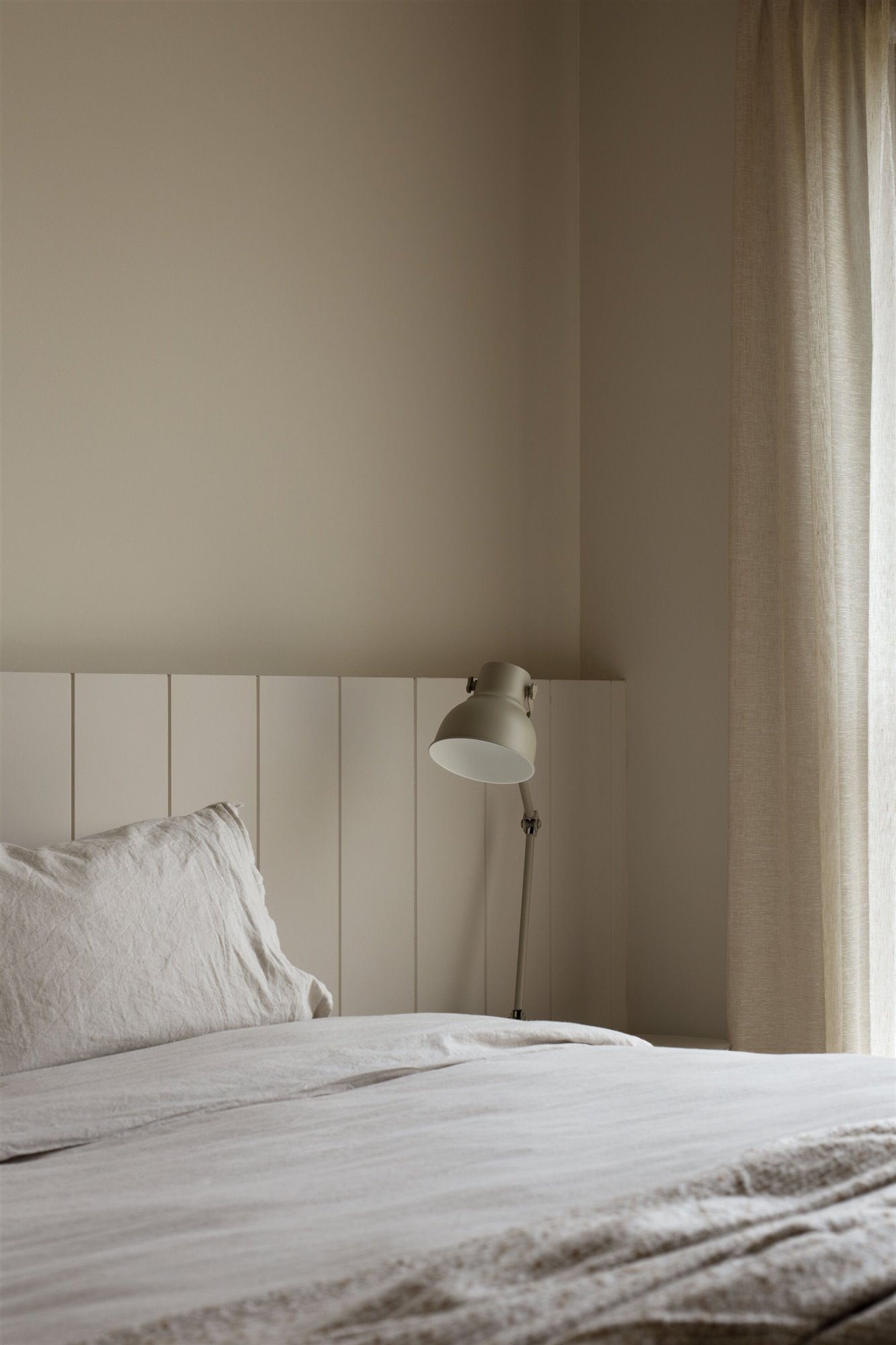 Dormitorio de tonos neutros con cama con lampara en mesilla de noche