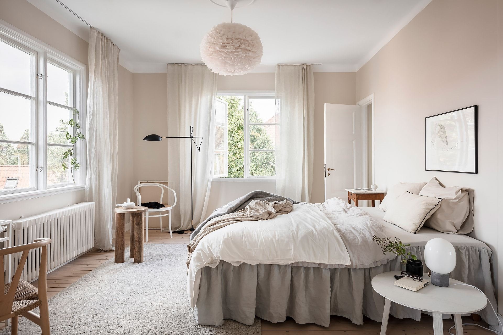 Dormitorio en color beige con ropa de cama gris lampara tipo pompon en el techo y alfombra