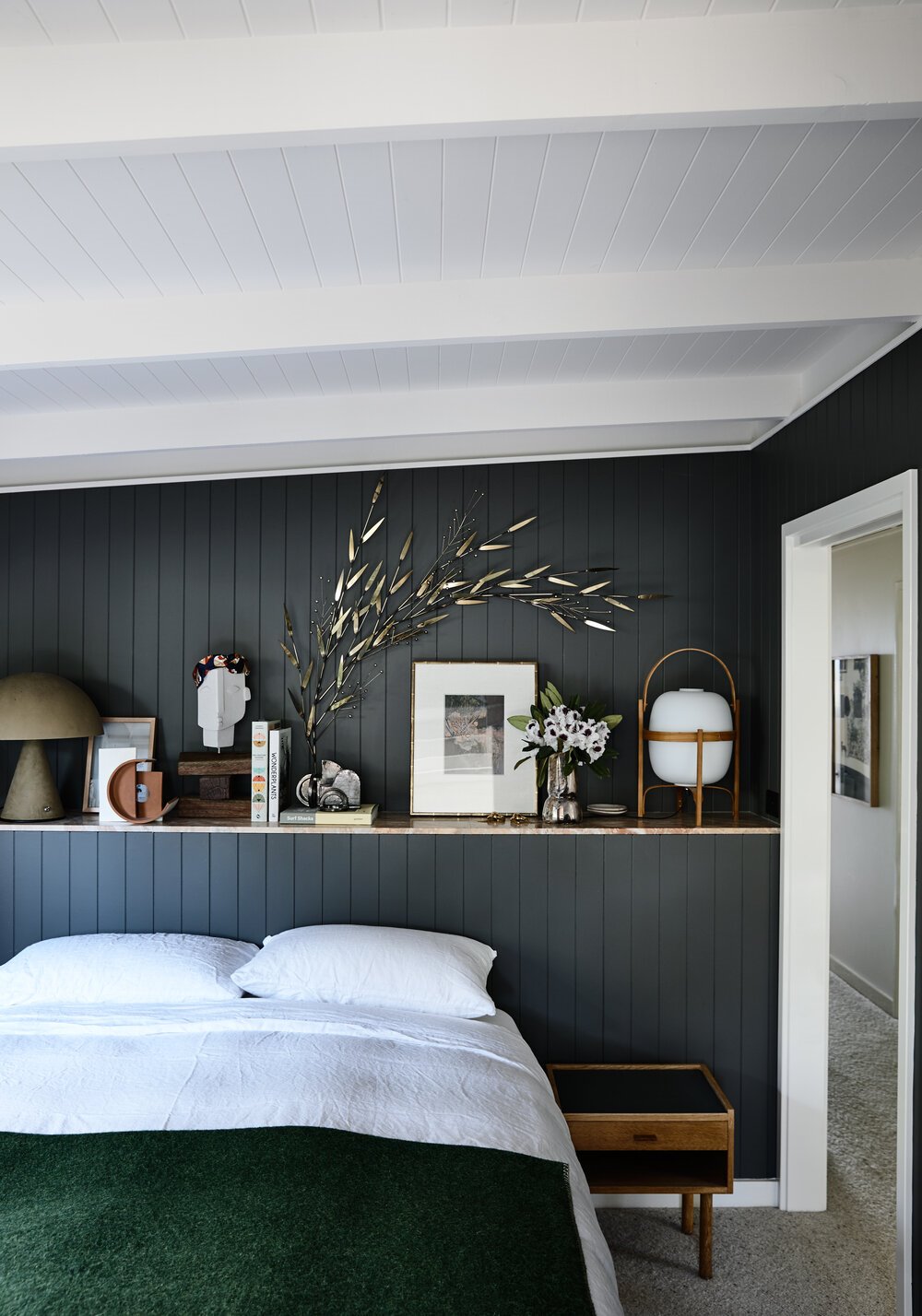 Dormitorio con paredes de tablones de madera y balda con objetos decorativos lampara cestita santa cole