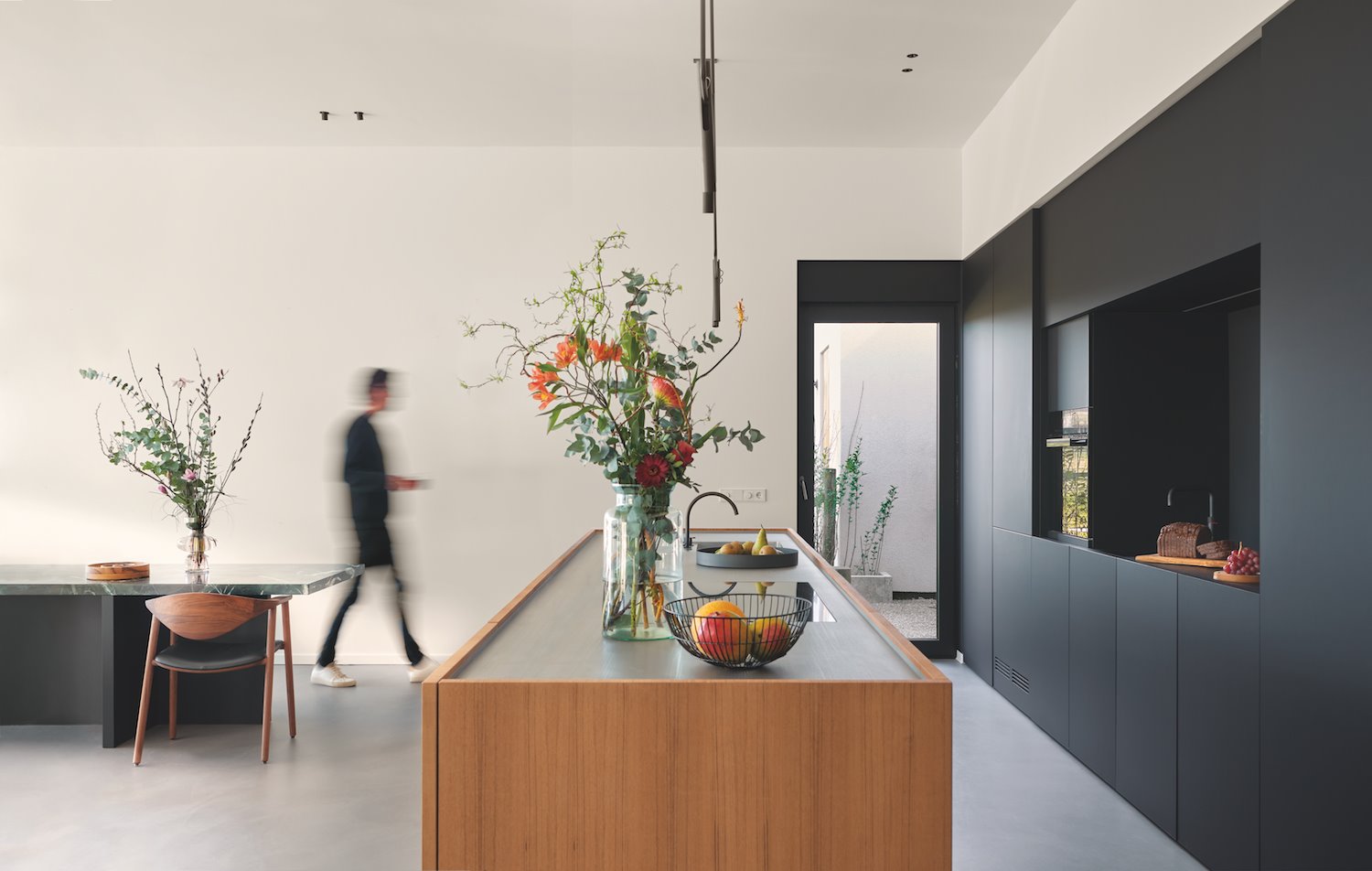 Cocina con muebles de color negro y comedor con mesa de marmol