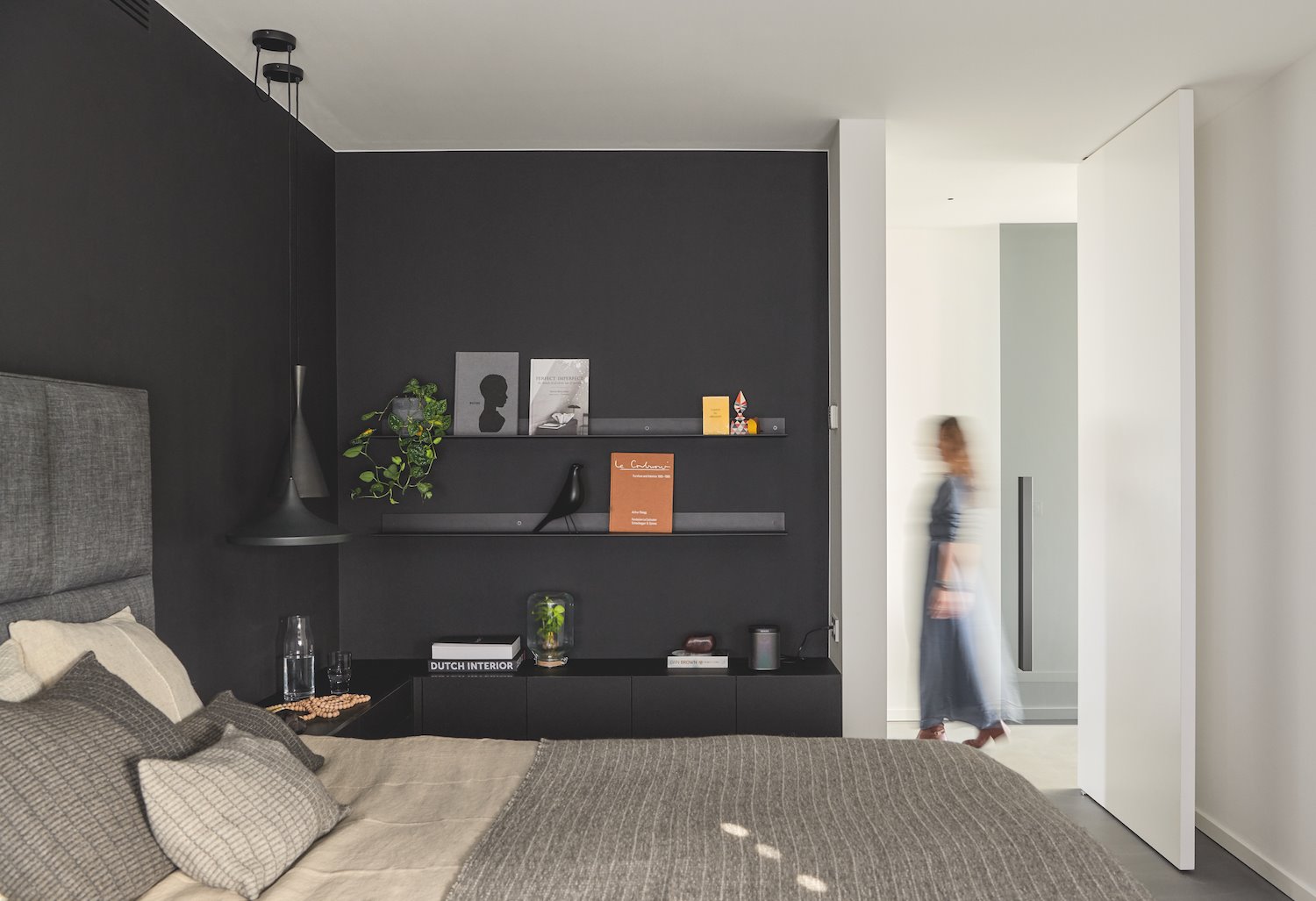 Dormitorio con cabecero de tela de colro gris y paredes pintadas de color negro