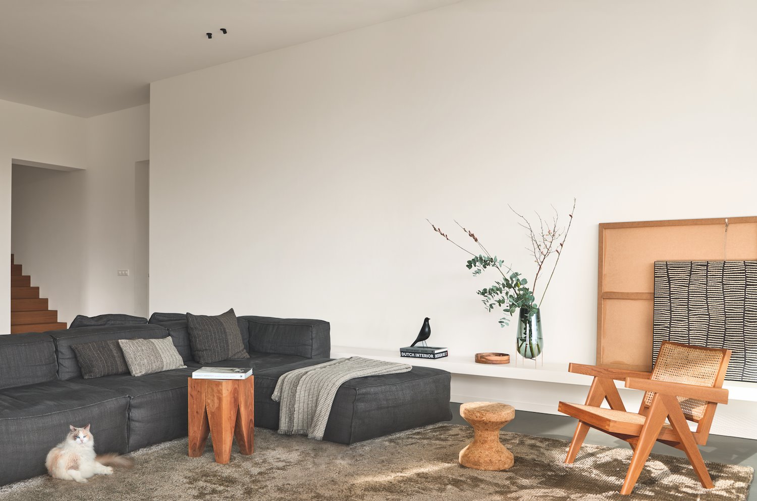 Salon con sofa de tela gris y sillas de madera gato