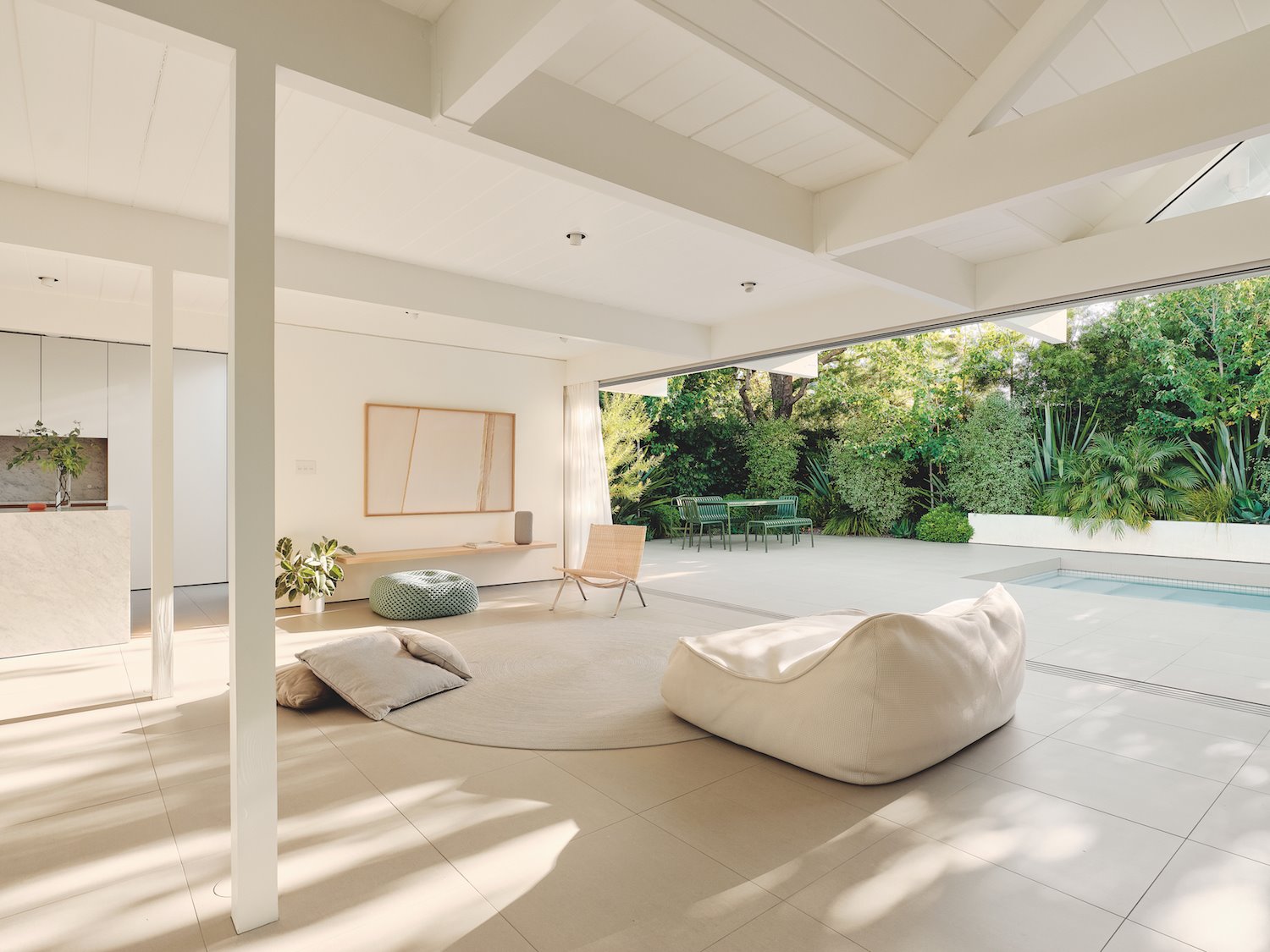 Salon abierto de una casa moderna blanca con sofá blanco y cocina