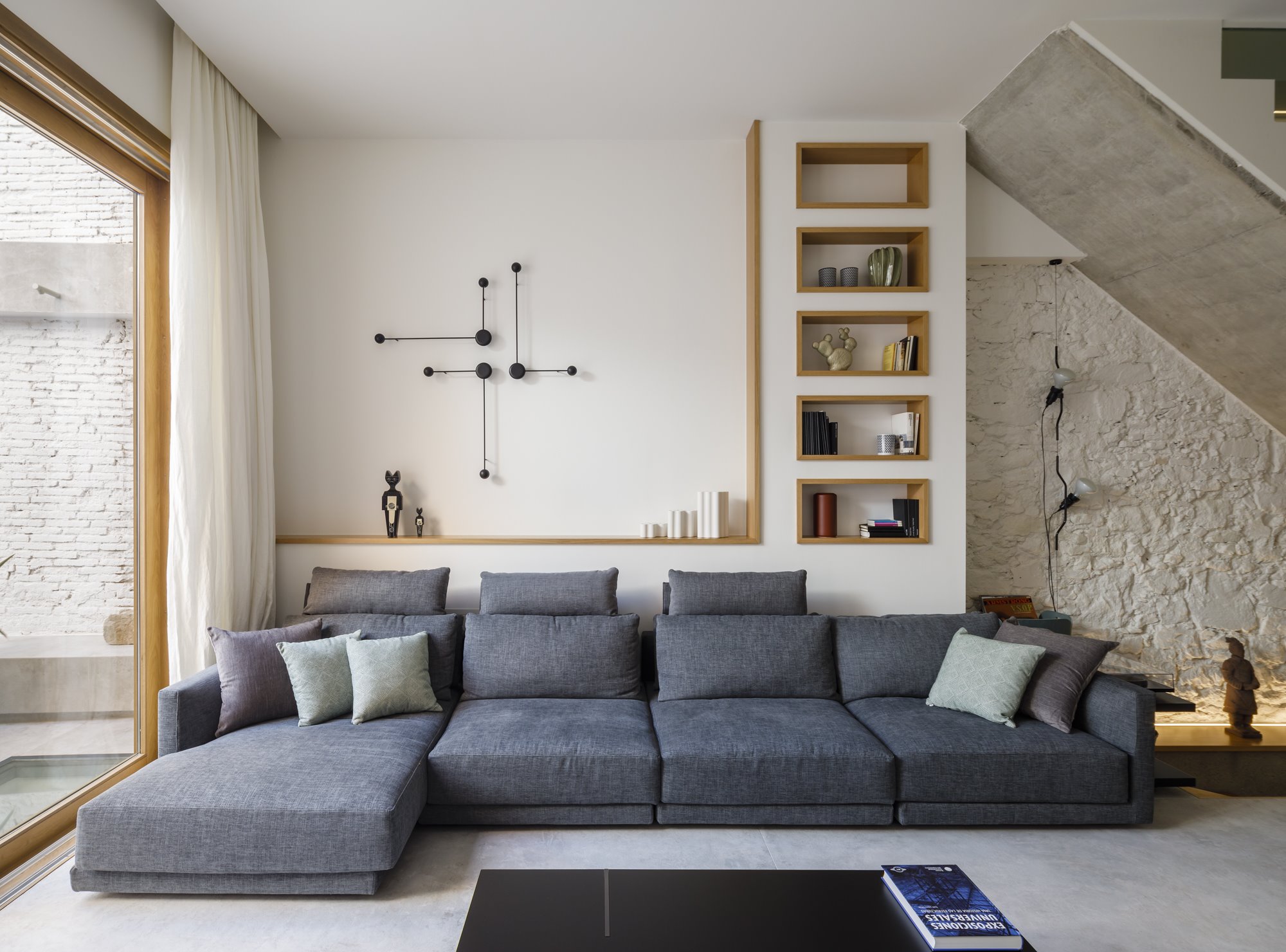 Salon con sofa con reposapies y estanterias de obra