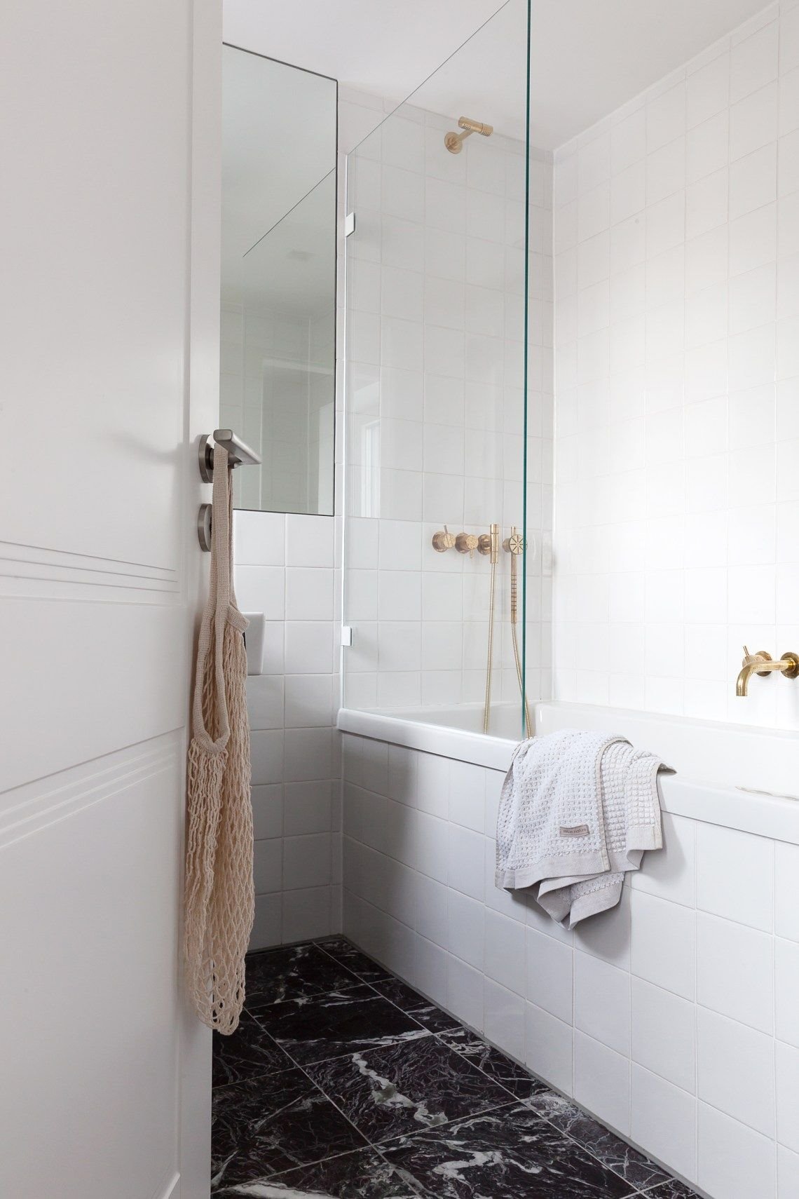 Baño con bañera suelo de color granito oscuro griferia dorada