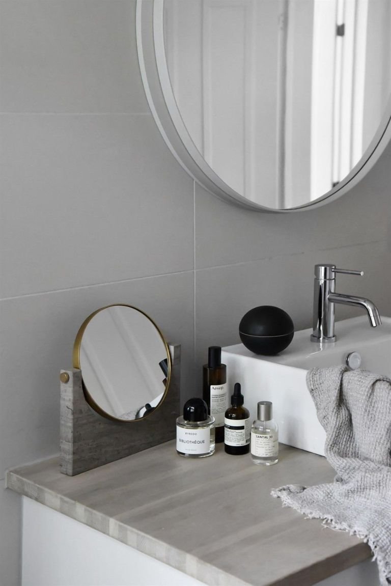 Baño con encimera gris y espejo redondo