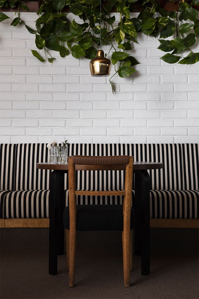 Savoy-restaurante-interiores-Helsinki-Ilse-Crawford-Mesa y planta.  La pareja concibió sus interiores para incorporar una sensación de comodidad e intimidad, con maderas ricas y exuberantes plantas, y un uso vívido de las telas.