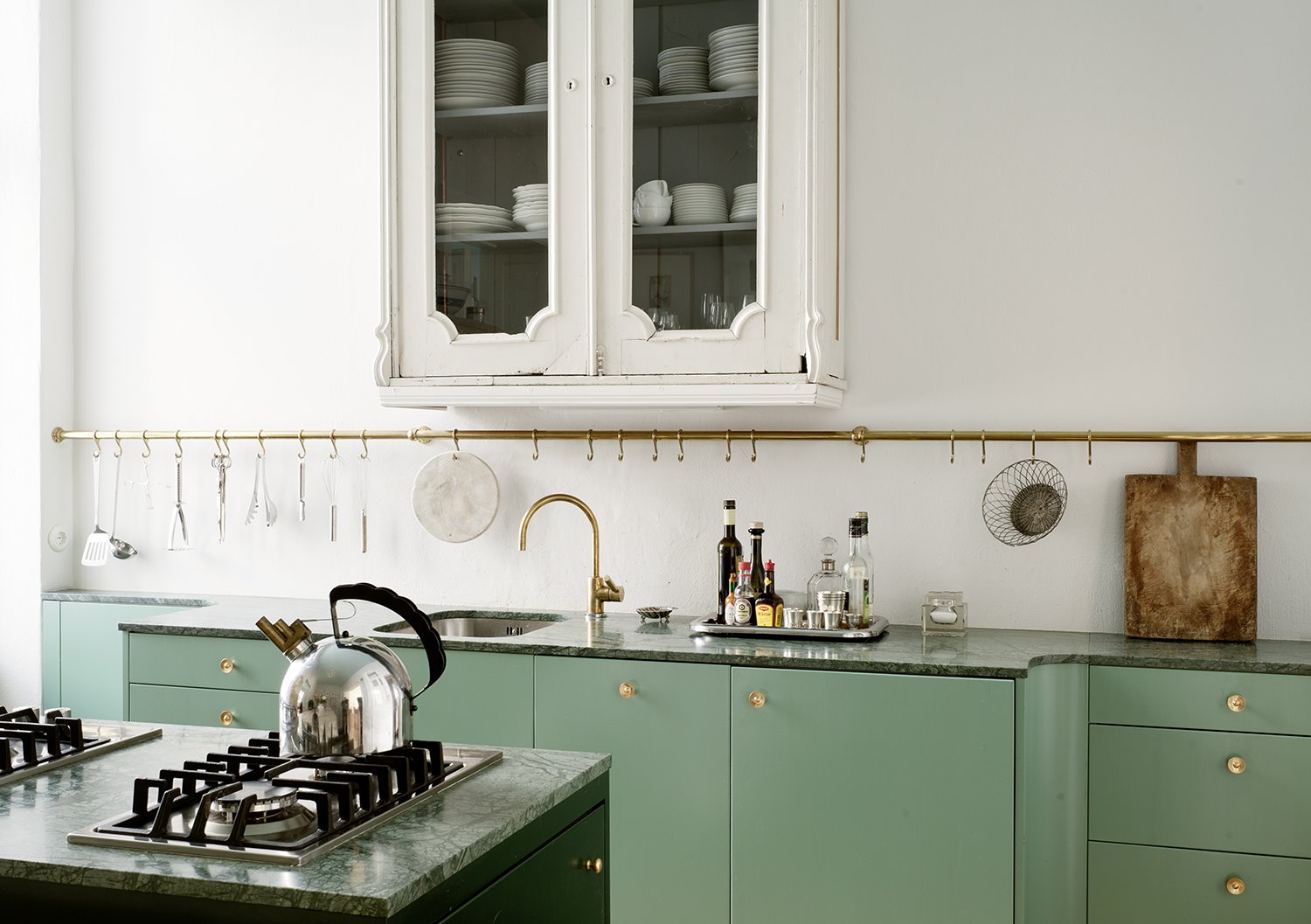Cocina con muebles con frontales de color verde y barra de color dorado