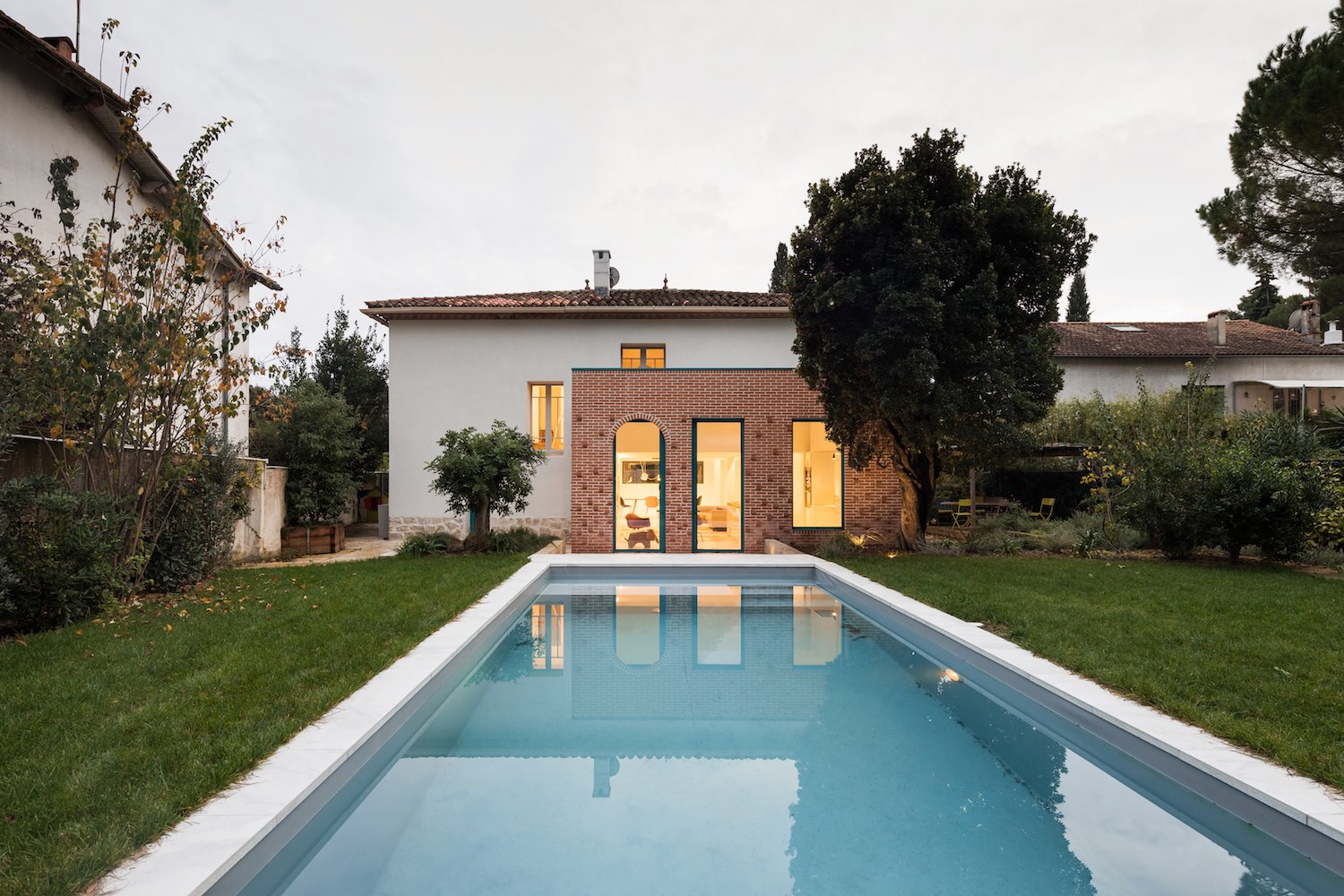 Extensión de una casa moderna con un bloque de ladrillo junto a una piscina