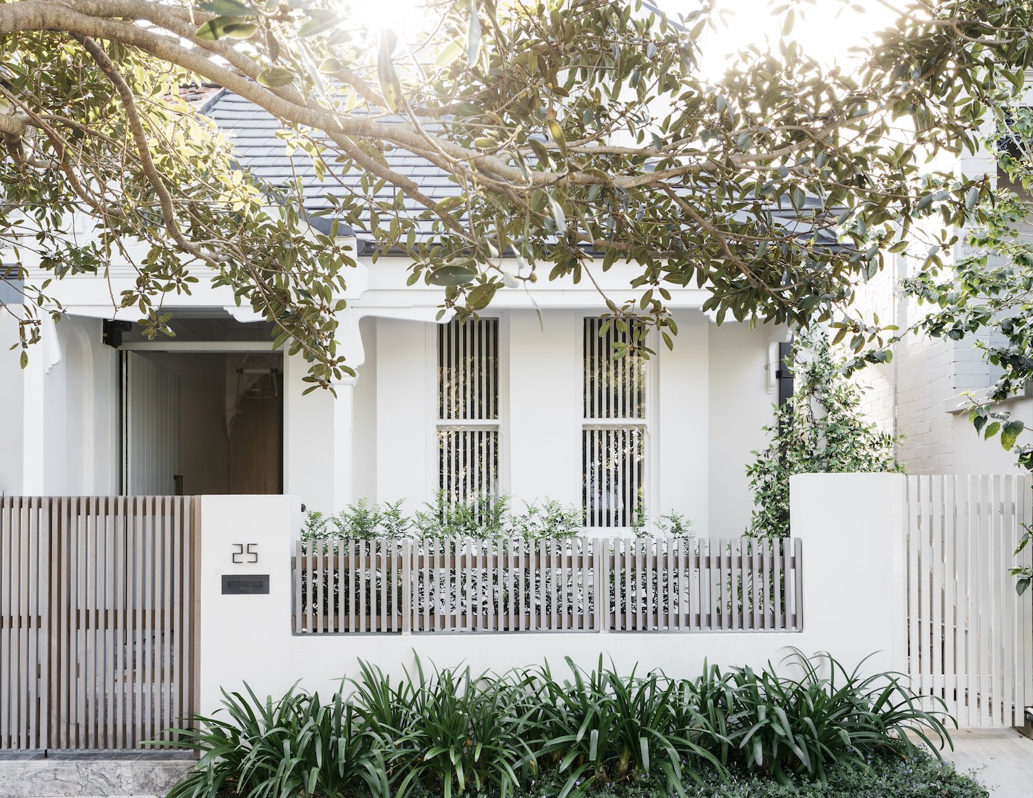 Fachada con jardin valla y paredes blancas
