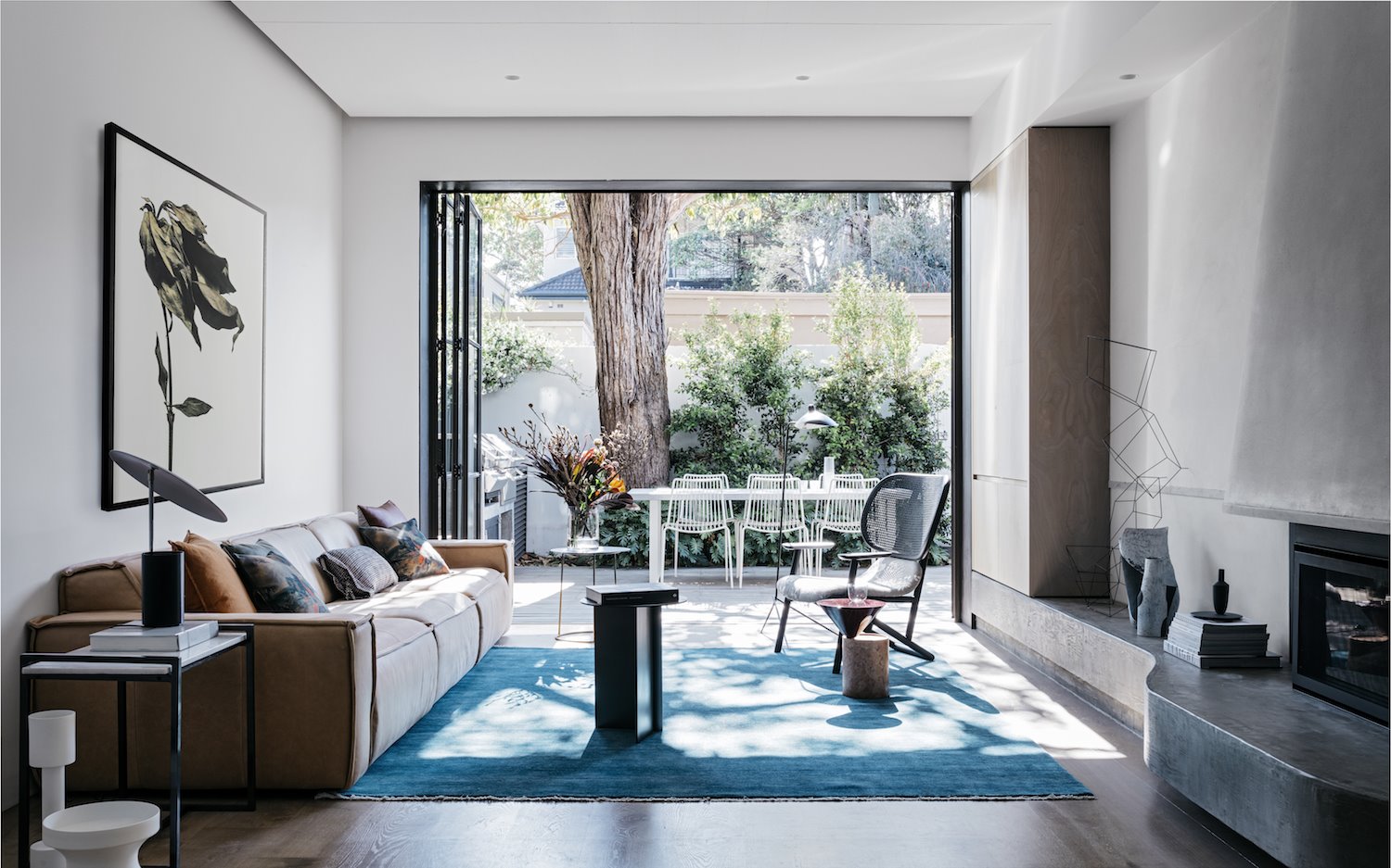 Salon abierto a un patio con alfombra azul y sofá de piel marrón