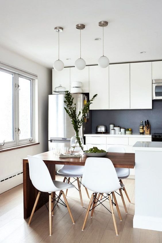 Cocina con mesa añadida a la barra de cocina sillas de plastico y lamparas de techo