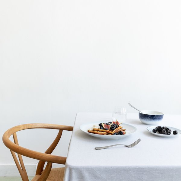 Mesa con manteleria blanca y platos de Wik & Walsoe