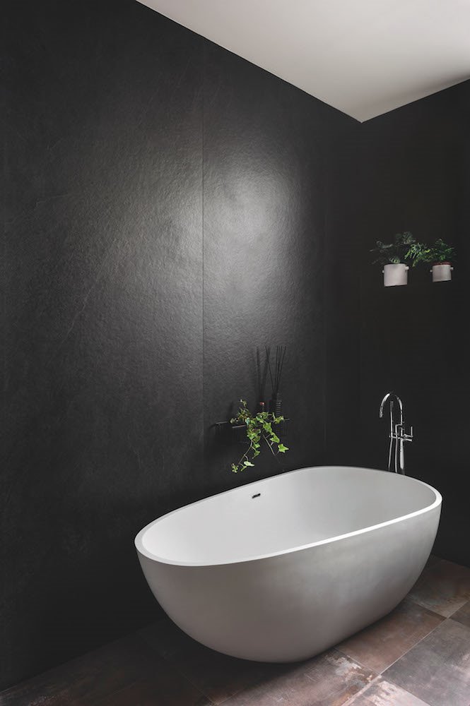 Baño con bañera blanca y paredes de color negro
