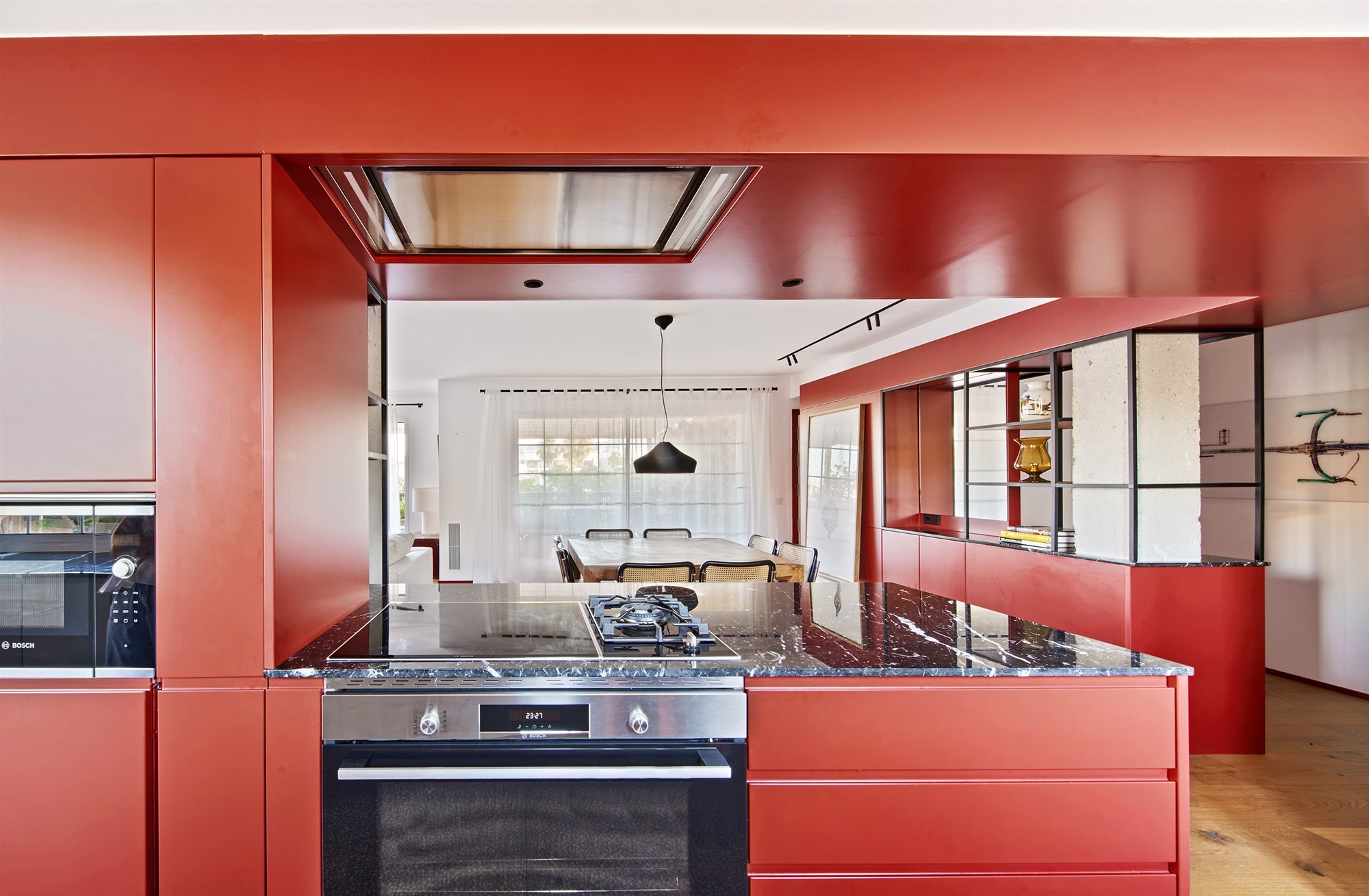 Cocina con fuegos de gas y encimera de marmol de color negro muebles de color rojo