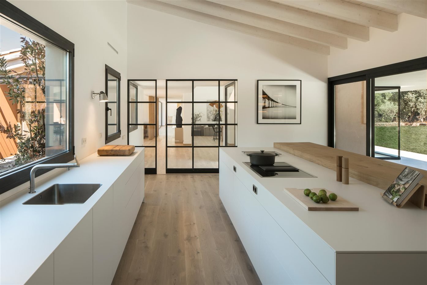 Cocina con vigas de color blanco y puertas de cristal con marco de color negro