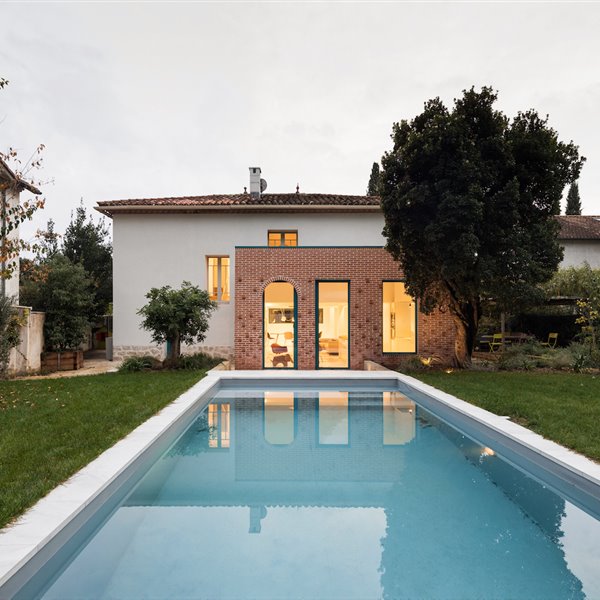 Extensión de una casa moderna con un bloque de ladrillo junto a una piscina
