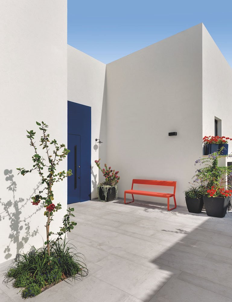 Patio con puerta de color azul y banco de color rojo