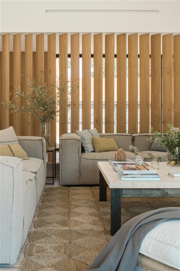 Salon con sofa gris separaciones de madera y alfombra de fibras naturales