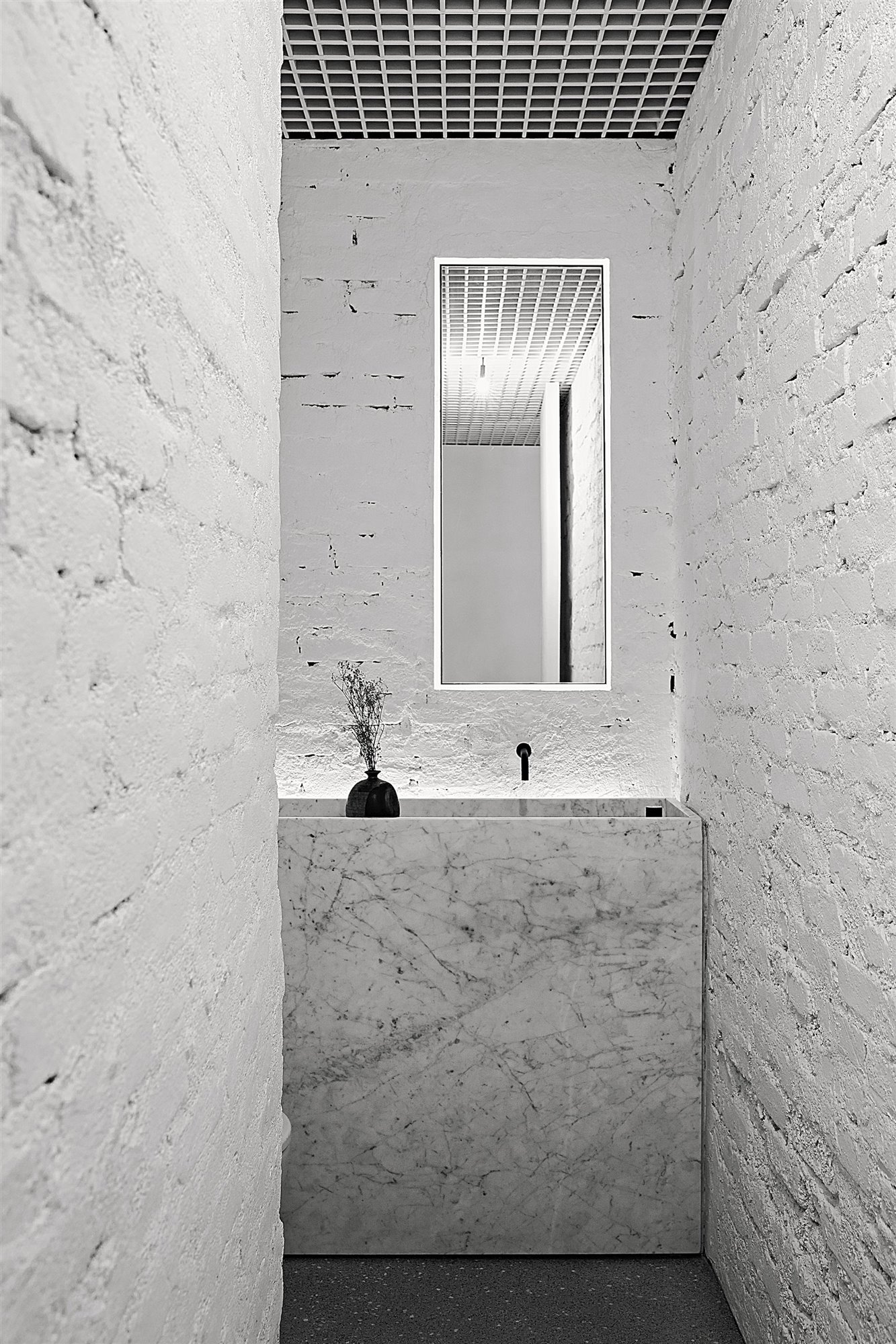 Baño con paredes de ladrillo blanco y mueble de marmol