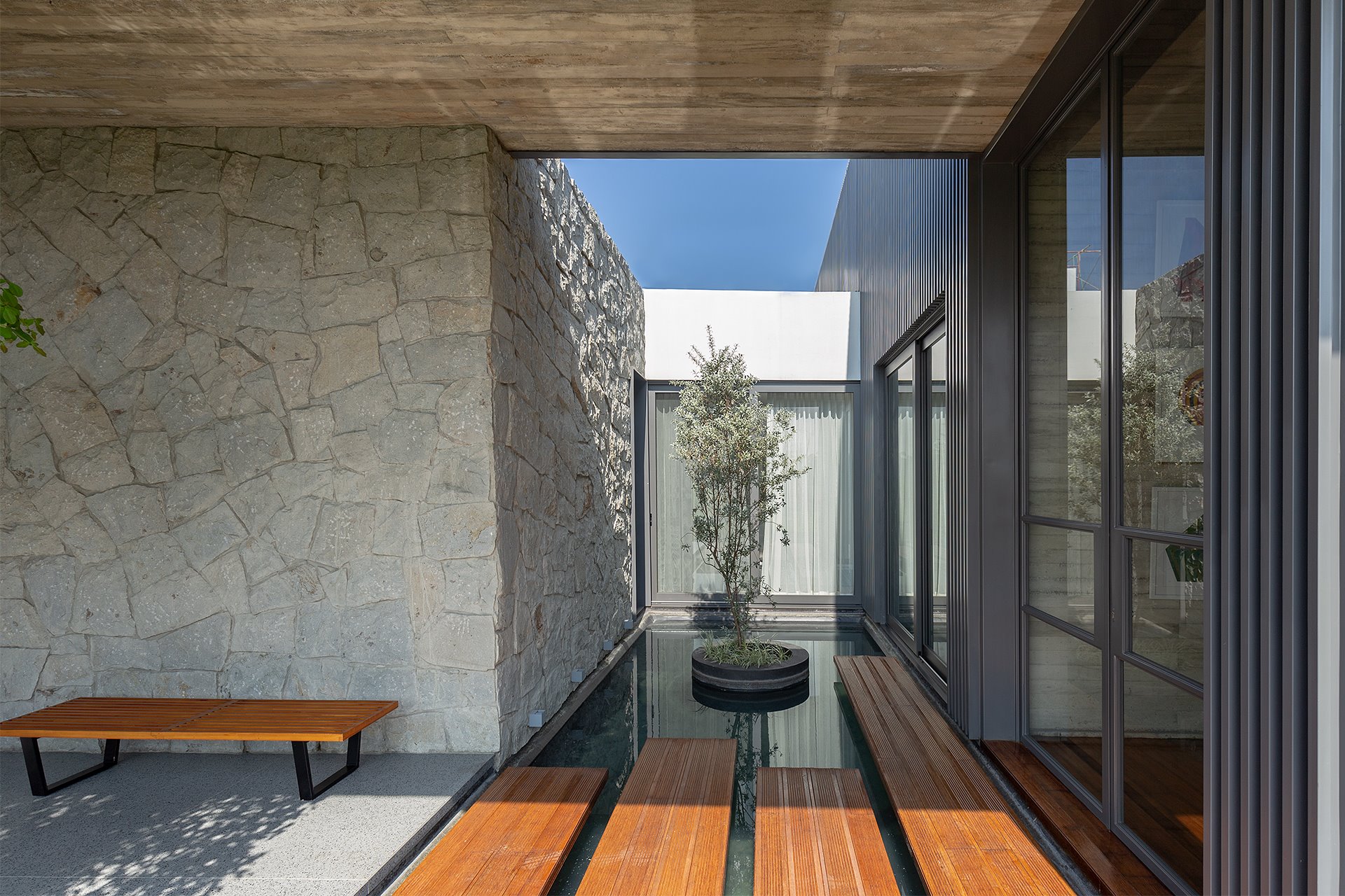 Casa moderna con paredes de piedra y un lago con tablas de madera