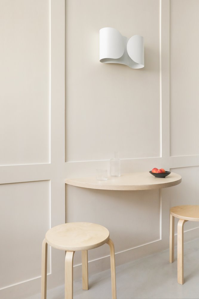 Comedor con una mesilla de madera pegada a la pared y taburetes de madera
