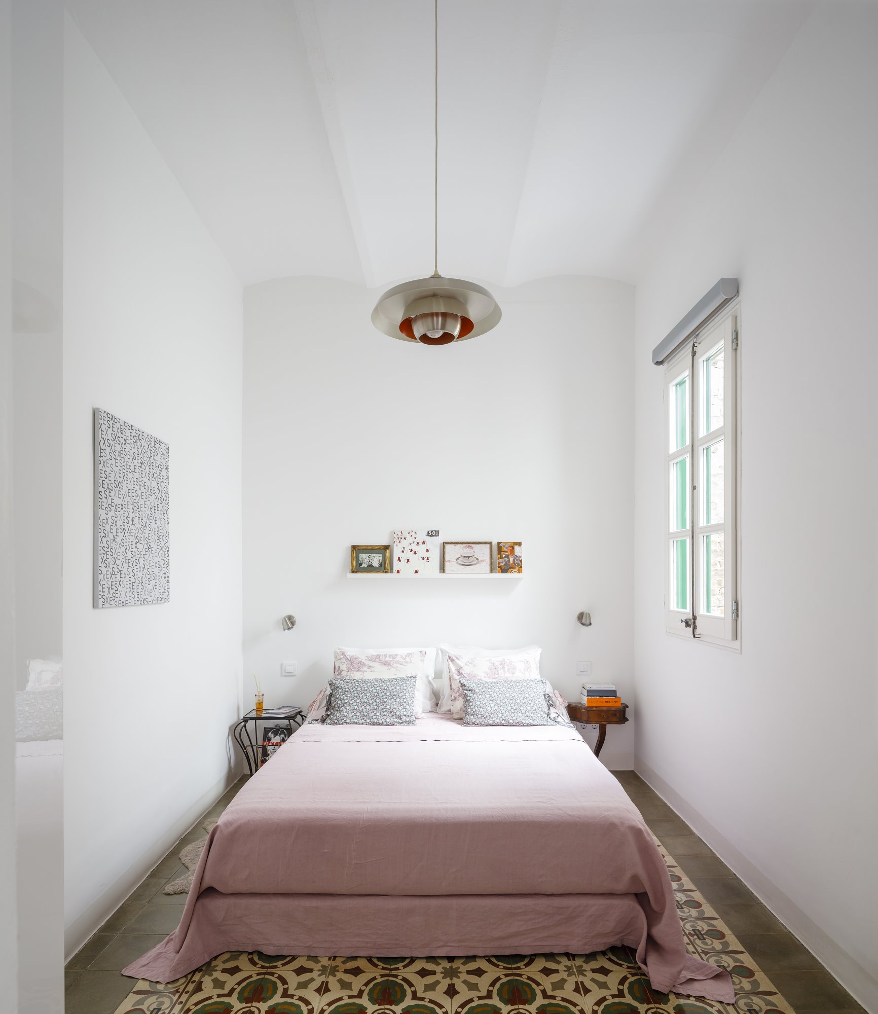 Dormitorio con suelo hidrauliso y techo con vigas de un piso rehabilitado en Barcelona